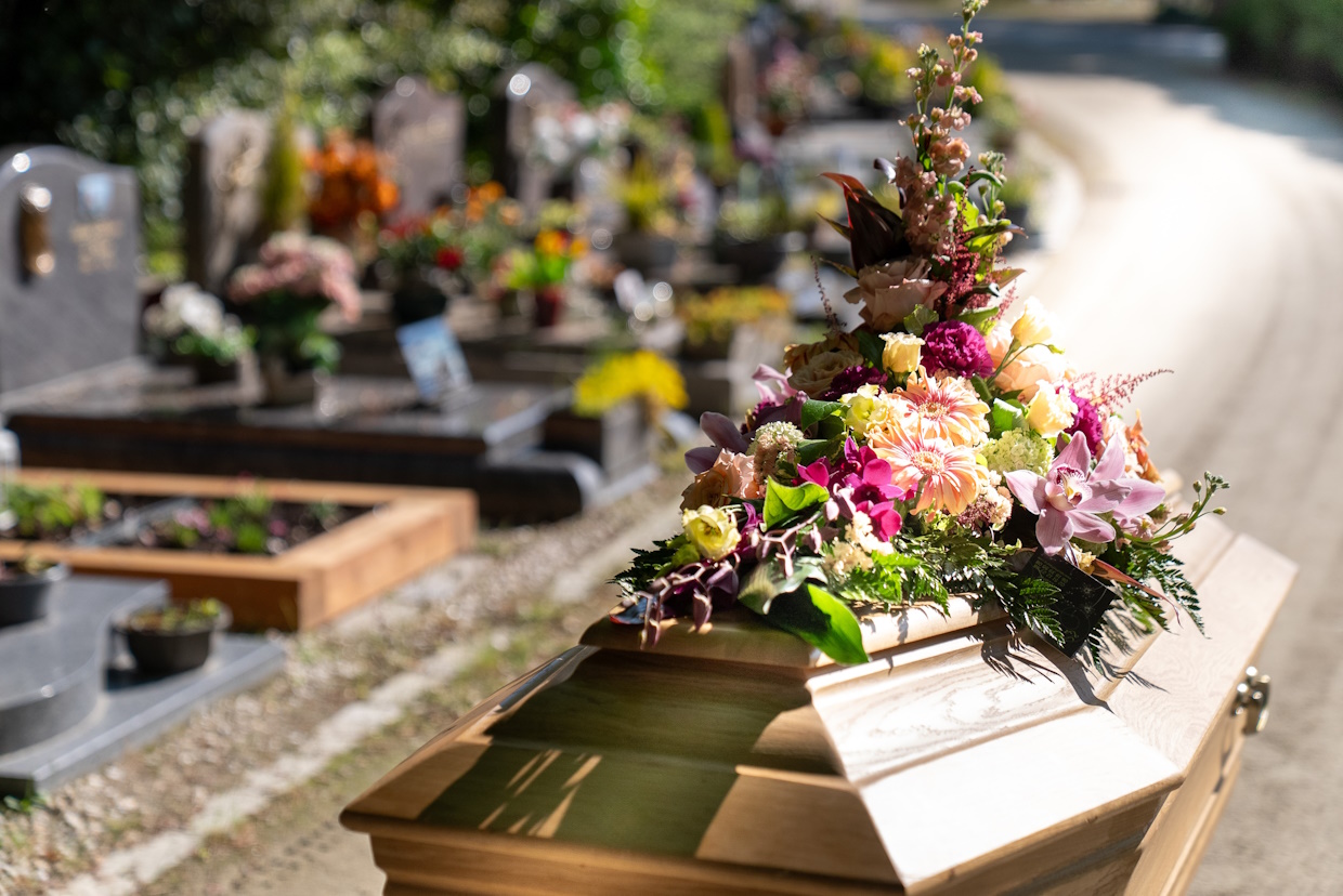 Cercueil avec fleurs dans un cimetière ensoleillé.